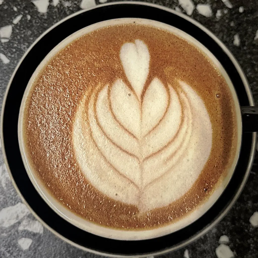 Un caffè latte recién hecho muestra un delicado arte de espuma en capas, reflejando la suave mezcla de espresso y leche vaporizada en esta popular bebida de café.