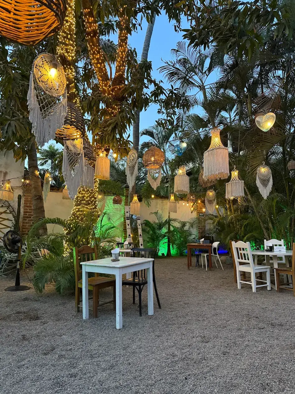 Lanterns flicker through lush tropical greenery as couples share wine beneath palm fronds at Chaman Garden — a romantic hideaway along the Nayarit Coast.