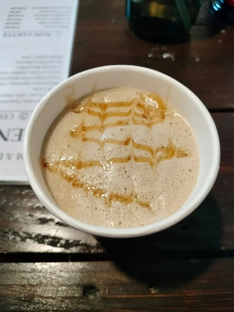 Un flat white caliente en una taza sencilla presenta microespuma sedosa y un toque de caramelo, mostrando la unión suave de espresso y leche.