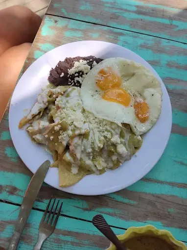 Crispy chilaquiles covered in salsa and queso are paired with black beans and sunny-side-up eggs, creating a hearty morning plate at La Chilaqueria