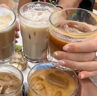 Amigos levantan vasos de café frío en un alegre brindis en Miscelánea Café, capturando un refrescante momento de conexión y energía matutina en Sayulita.