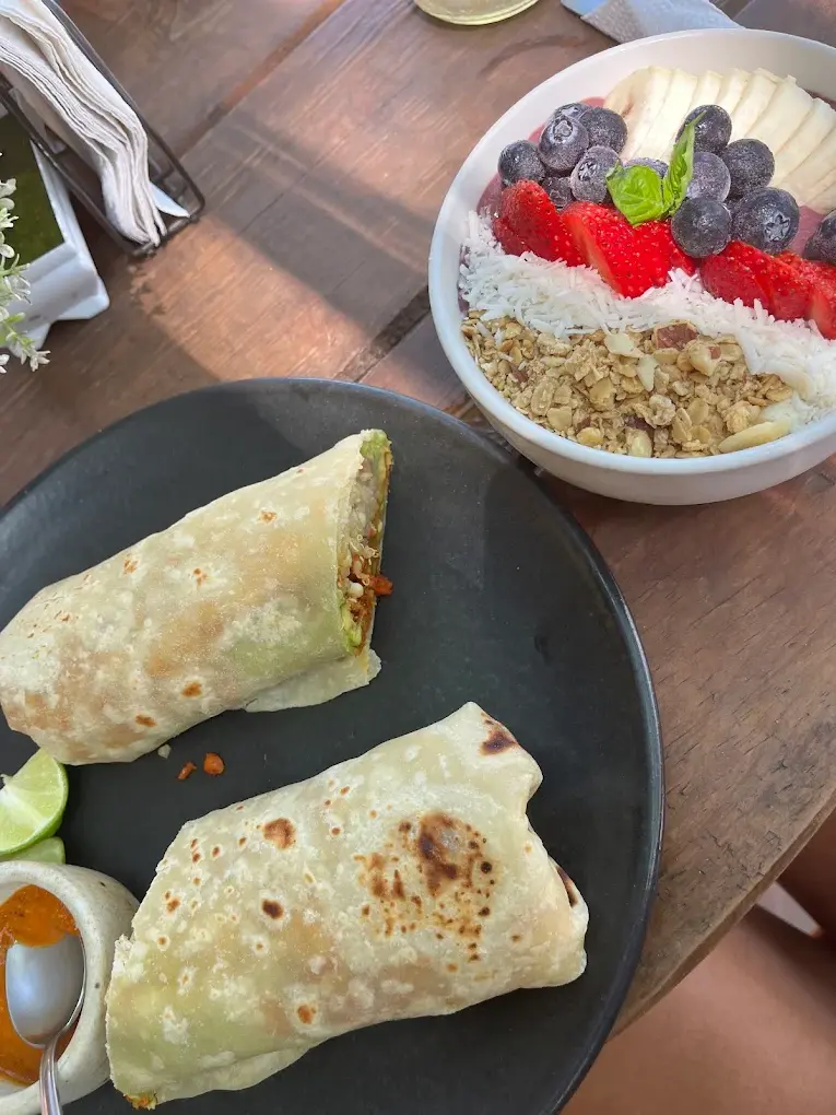 A warm vegan breakfast burrito sits beside a colorful berry-and-coconut bowl, creating a wholesome, plant-forward morning meal at Northswell