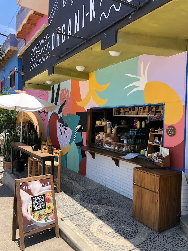 A colorful mural and counter welcome guests to Organi-K, offering bright seating, fresh breakfast bowls, and easy walk-up service in Sayulita