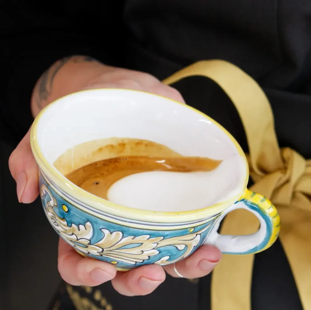 Un cappuccino recién preparado descansa en una taza de cerámica artesanal, mostrando su espresso profundo y espuma suave, reflejando el atractivo refinado de esta bebida.