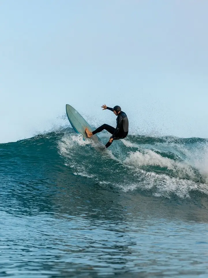 A surfer cuts cleanly through blue ridges of morning swell—rhythm and freedom on the Pacific Riviera Adventure Line.