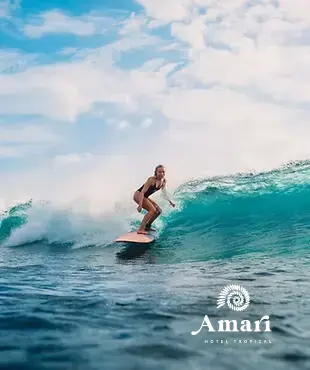 Surfer rides blue waves near Amari Spa Hotel — a Riviera Nayarit boutique lodging uniting adventure and ocean tranquility.