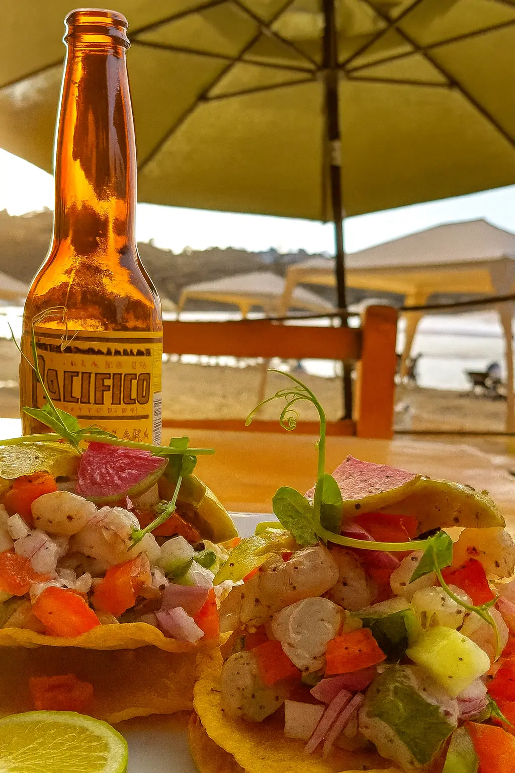 Bocadillos ligeros y una bebida fría descansan sobre una mesa al sol, reflejando sabores costeros sin complicaciones.