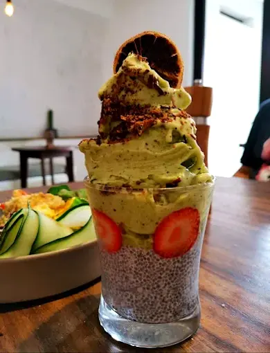 Matcha smoothie swirled over chia pudding with fresh strawberries and a citrus garnish creates a bright, nourishing breakfast option at Anchor Café