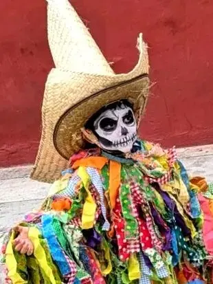 Young boy with calaca face paint smiles amid marigolds — a conscious celebration of memory, artistry, and Sayulita’s local joy.