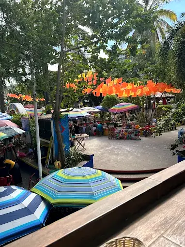 Colorful umbrellas, papel picado, and lively plaza stalls create a vibrant morning scene as guests enjoy breakfast on the terrace at Chocobanana in central Sayulita