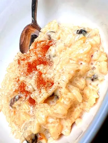 Arroz con leche in a bowl topped with cinnamon and raisins, highlighting creamy rice pudding texture, gentle spice, and the simple comfort it offers.