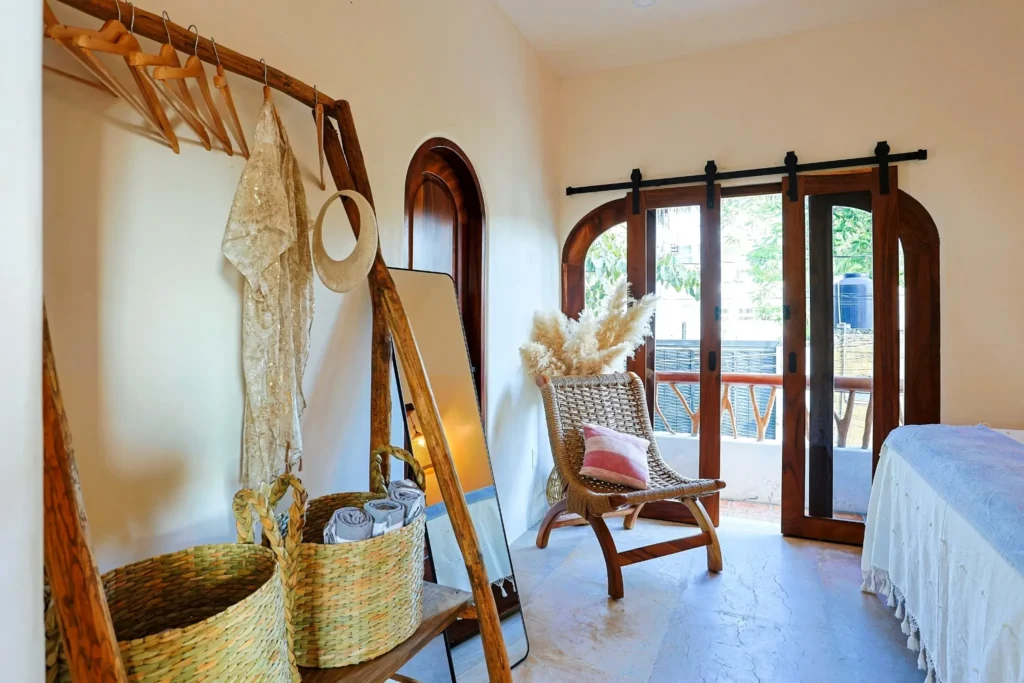 Bedroom entry with wardrobe rack, woven baskets, mirror, and balcony doors—easy long-stay comfort at Amari Hotel.