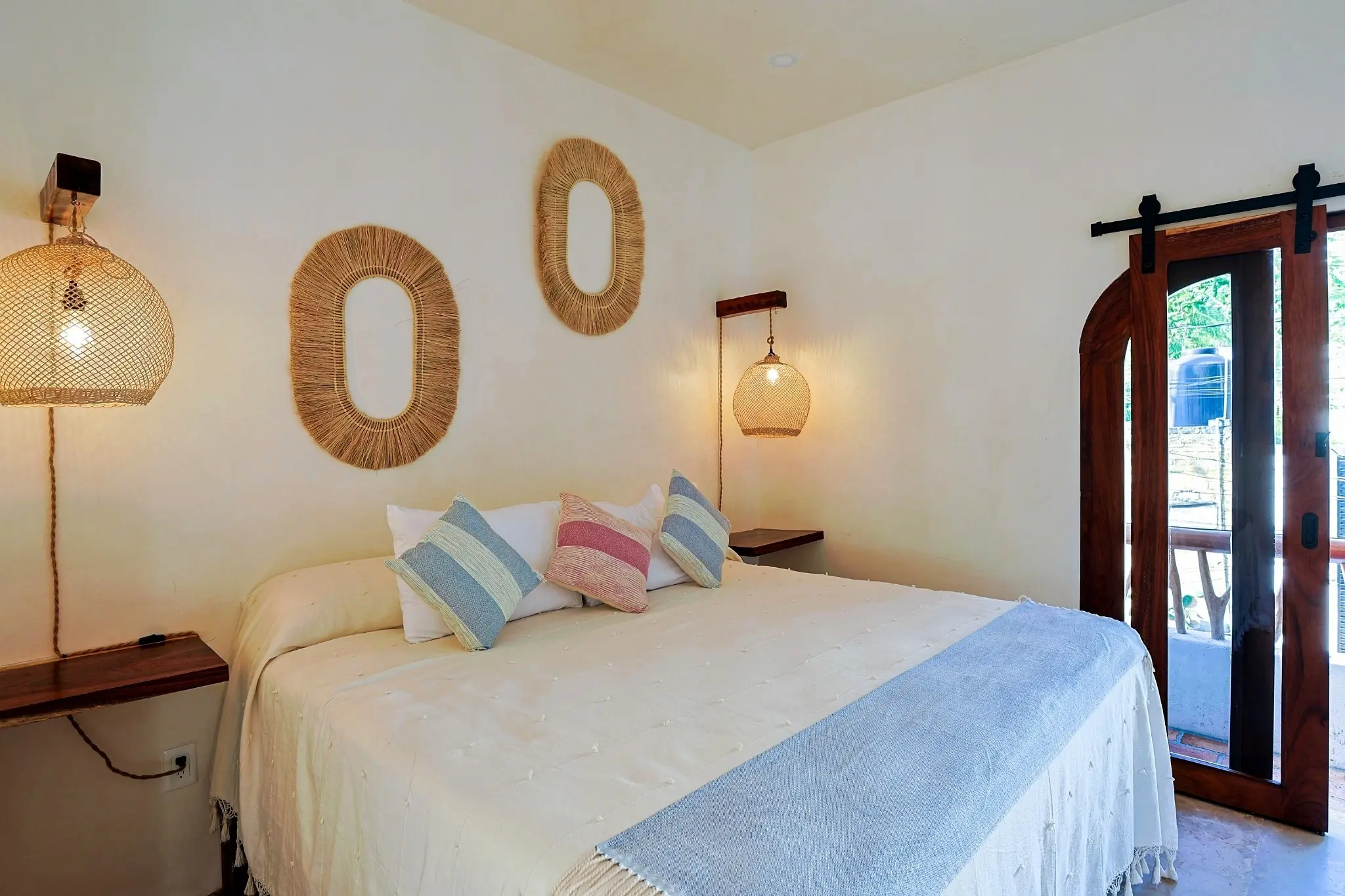 King Bedroom With Woven Lighting, Textured Wall Decor, and Balcony Doors
