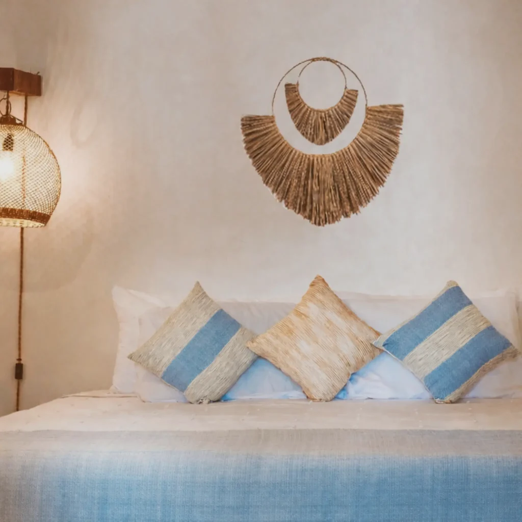 Sunlit bedroom with woven wall art, fresh white linens, and blue accent pillows—an airy, soothing stay at Amari Boutique Hotel Sayulita