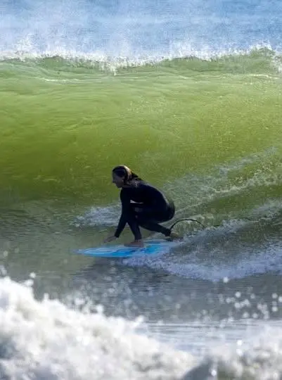 A surfer rides a glowing barrel at sunset, movement and color sweeping across a quiet stretch of the Pacific Coast at day’s end.