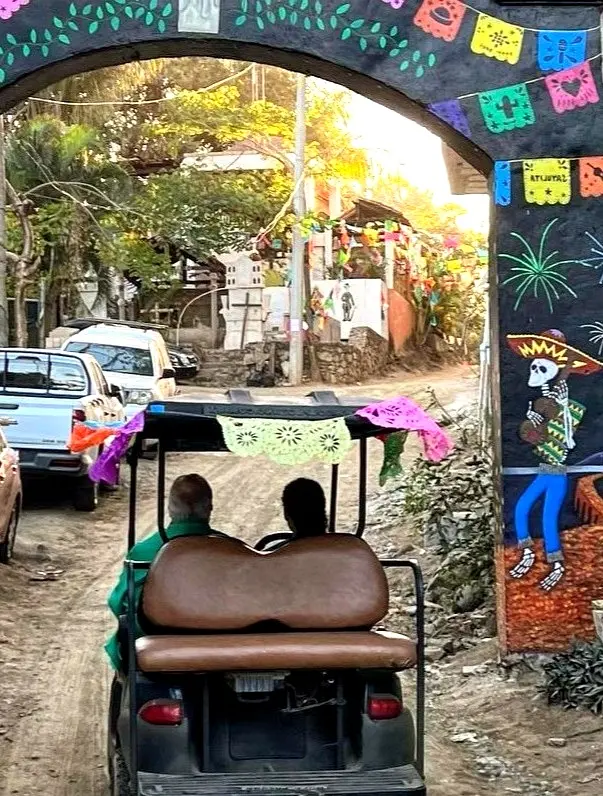A golf cart rolls beneath multicolored arches as music fills Sayulita’s lanes — a carefree way to explore the Riviera Nayarit village and nearby beaches.