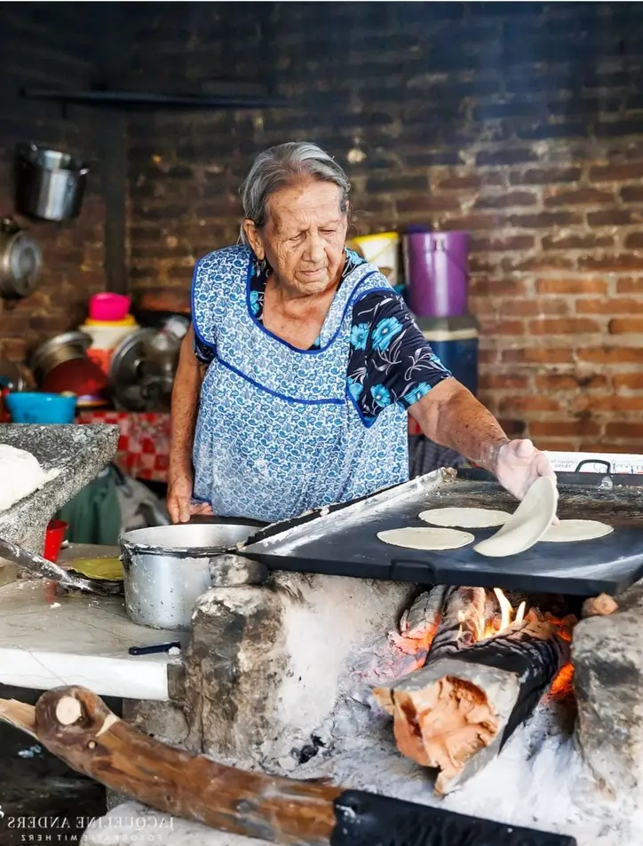 A local cook prepares handmade corn tortillas on a wood-fired comal showcasing Sayulita’s traditional cooking methods and authentic food culture.