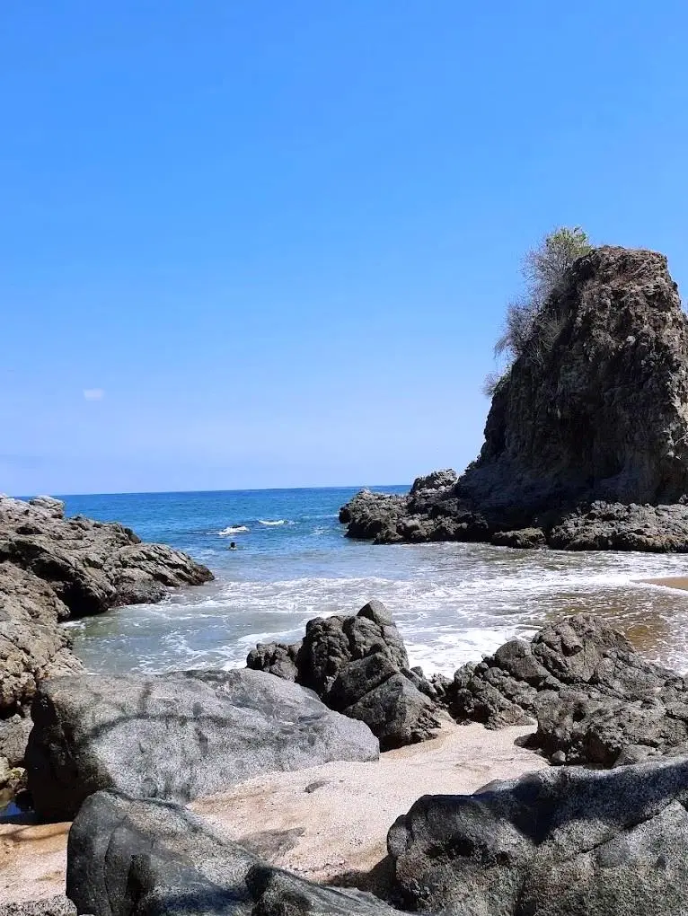 Waves curl between weathered rocks in a hidden cove, salt air and morning light shaping a quiet pocket along Pacific beaches.