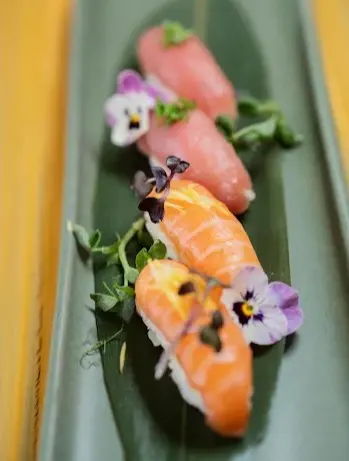Fresh salmon and tuna nigiri at Kabuki garnished with microgreens and edible flowers on a minimalist platter, known for casual sushi and affordable pricing.