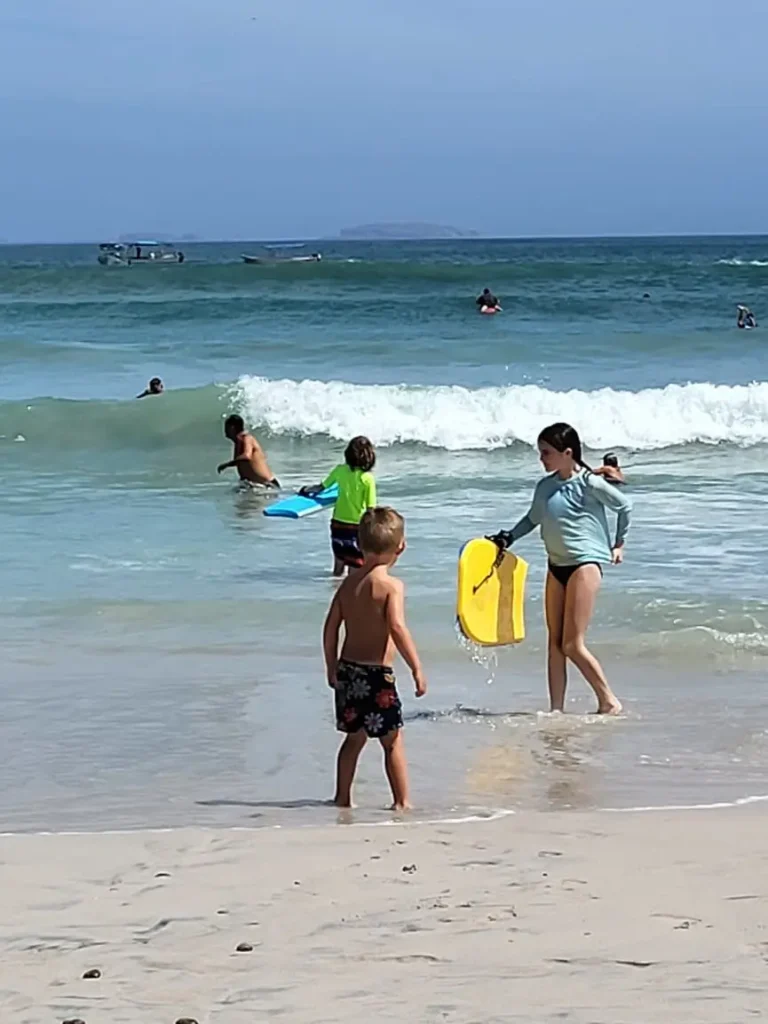 Children ride sparkling morning waves under soft light—joy and laughter along the Riviera Getaway on Mexico’s Pacific Coast.