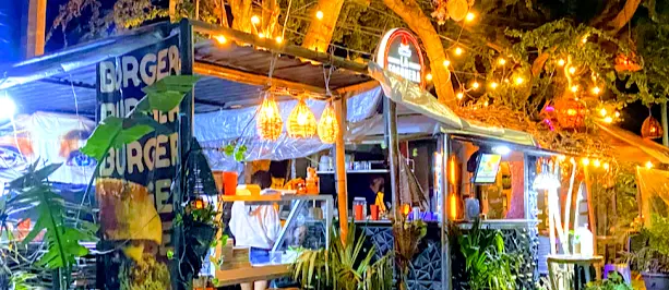 String lights and jungle greenery frame La Fogonera’s colorful food truck, where locals and travelers gather for late-night street burgers and music.