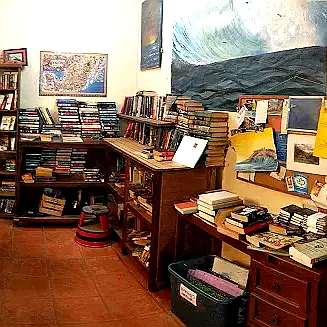 Pilas de libros y estanterías de madera cálida enmarcan un rincón de lectura tranquilo en La Librería, capturando el carácter familiar del café apreciado por los locales de Sayulita.