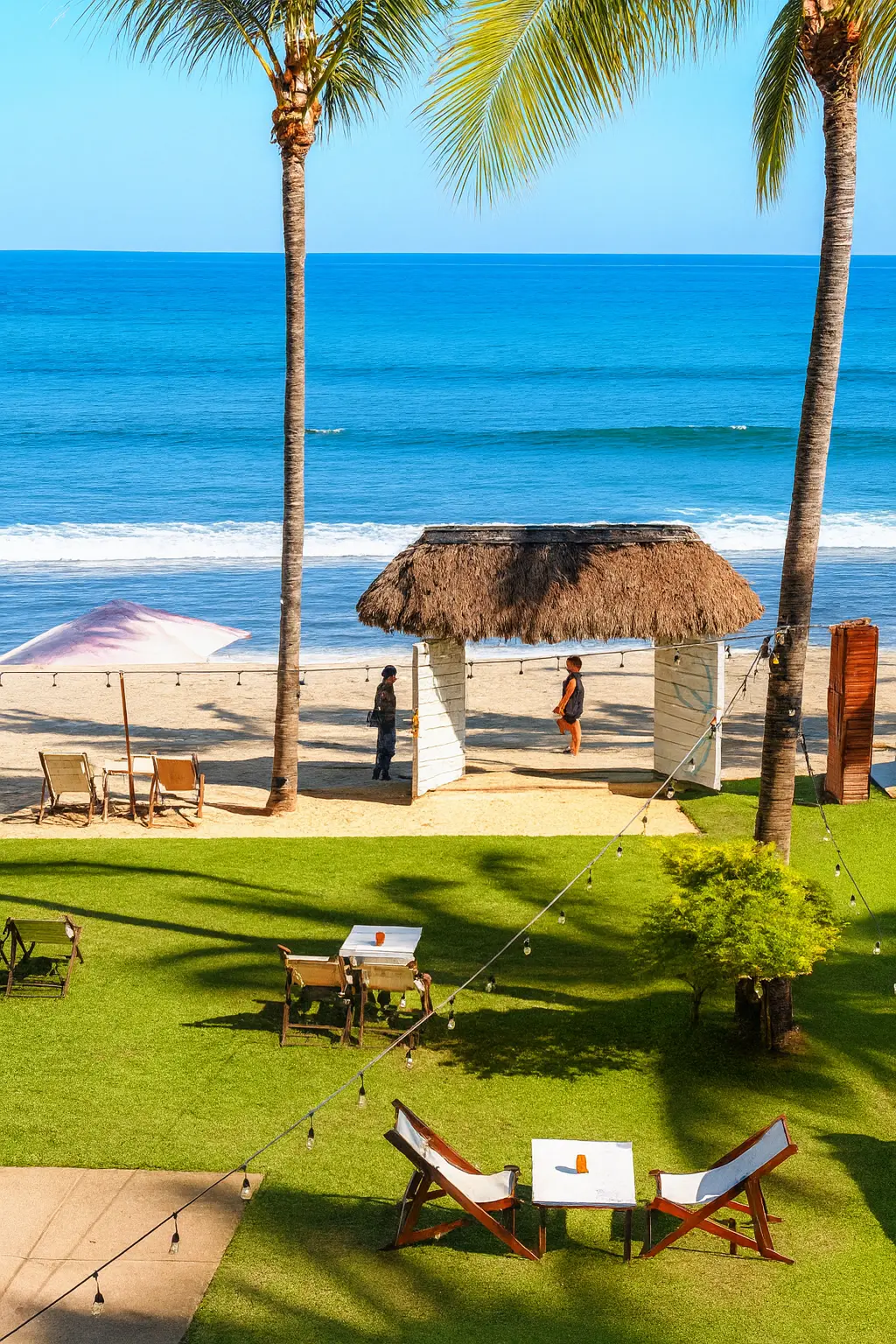 Mesas y sombrillas se extienden sobre un jardín relajado, ofreciendo espacio abierto para disfrutar comida y música.