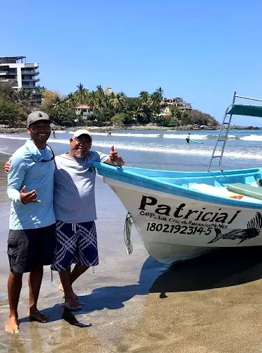 Anglers stand beside a beach-launched panga, reflecting the friendly culture travelers experience when booking local outings from Sayulita’s shores.