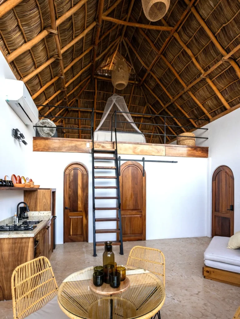 Suite loft de Amari con techo de palapa, cama acogedora en el piso superior, detalles hechos a mano y distribución abierta acogedora.
