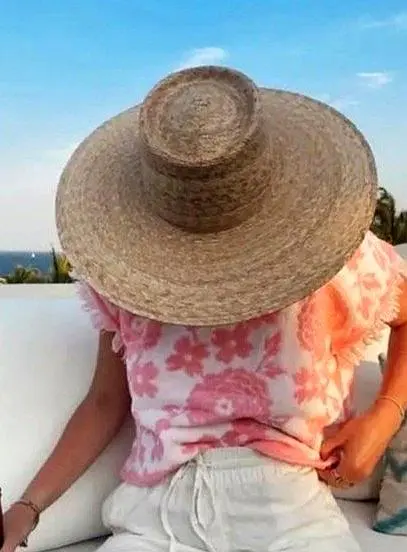 A traveler in a wide sun hat relaxes on a soft lounge cushion, taking a quiet afternoon pause and enjoying simple beach downtime with the ocean in view.
