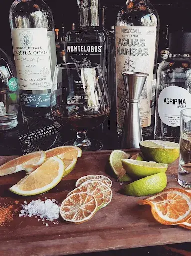 Selection of mezcal and tequila displayed with sliced citrus, salt, and a tasting glass, highlighting artisanal agave spirits served in Sayulita.