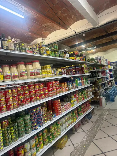 A long grocery aisle lined with canned goods, sauces, oils, and pantry staples arranged neatly on tall, well-organized shelves.