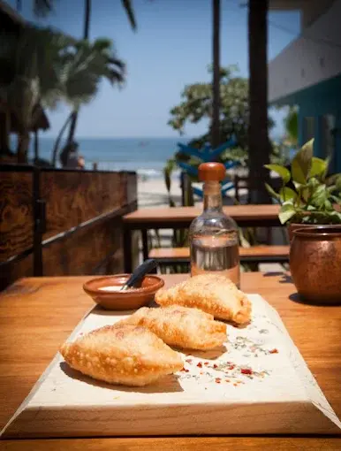 Crispy empanadas at a small oceanview restaurant in Sayulita, served on a wooden table with an easygoing coastal atmosphere ideal for a quiet lunch.