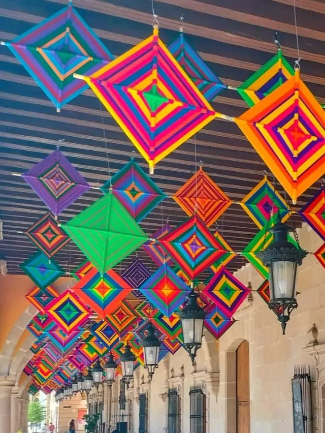 Vibrant Ojos de Dios yarn weavings symbolizing spiritual protection and artistry in Mexico’s Día de los Muertos tradition.