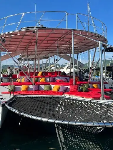 An open-air catamaran with cushioned seating is docked near Sayulita for a coastal outing beside the marina’s shoreline.