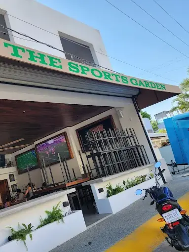 Open-air sports bar in Sayulita with TVs showing a live game, a motorcycle outside, and seating where people watch, cheer, and enjoy drinks.