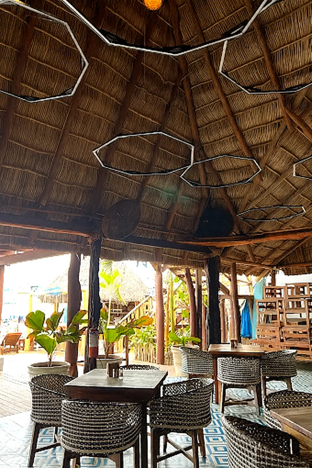 Luces cálidas, música y asientos bajo palapa crean un ambiente social animado que se extiende hasta la noche.