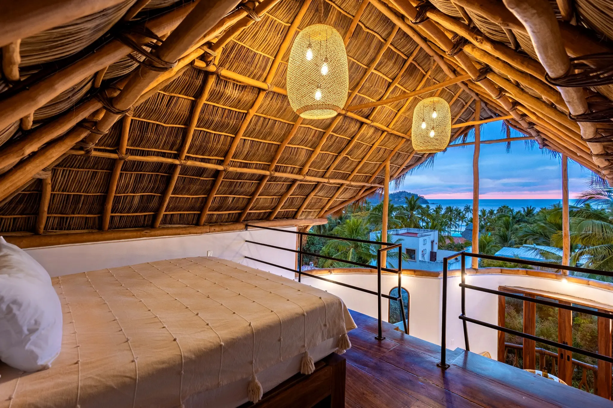 Lofted Bedroom With Woven Lanterns and Twilight Ocean Views