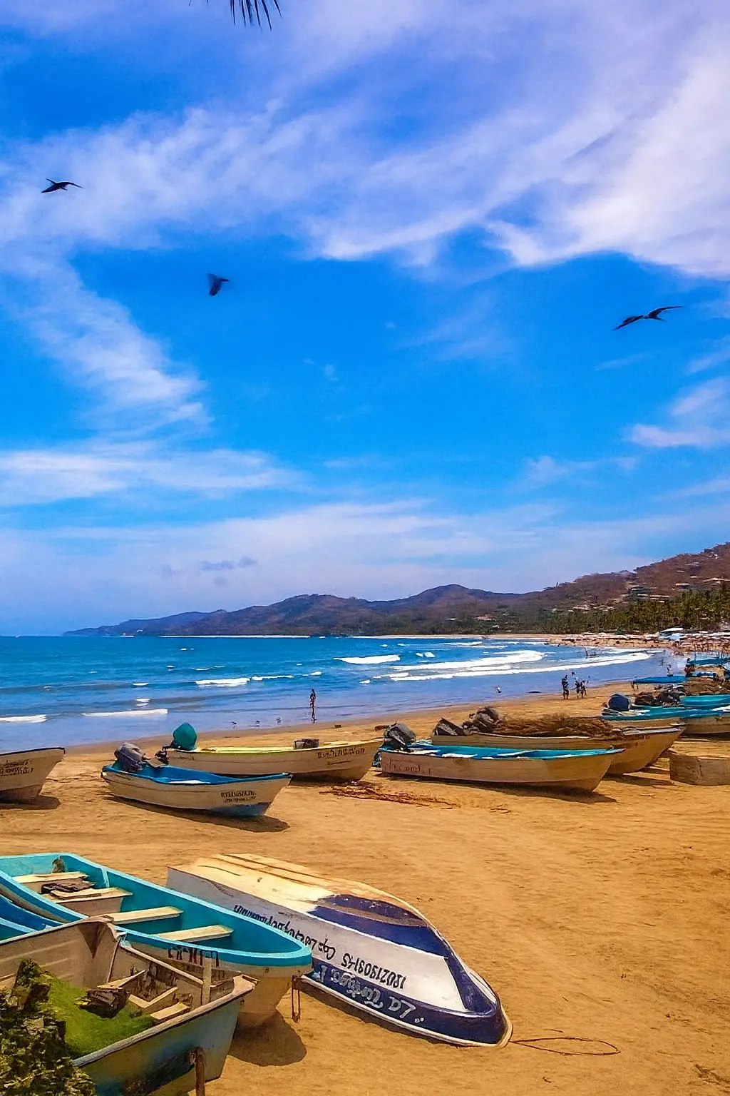 Una fila de pangas pesqueras descansa sobre la arena al amanecer mientras olas suaves llegan a Playa Sayulita.