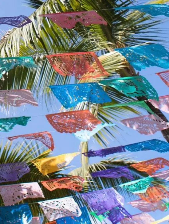 Intricate papel picado banners flutter, symbolizing the delicate veil between life and spirit in this Riviera Nayarit seaside resort.