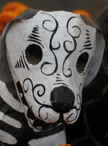A hand-painted papier-mâché skeleton dog with swirls and floral details, representing loyalty and spirit guides in Day of the Dead art.
