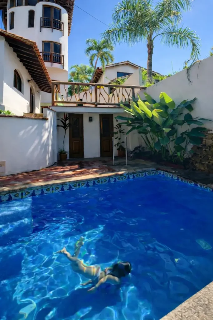 A young swimmer glides underwater in Amari’s saltwater pool, playfully mimicking a whale dive beneath the warm Sayulita sun and a tall palapa.