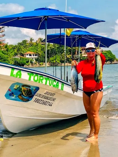 Fresh fish is held beside a panga, showing how many fishing trips in Sayulita begin directly from the beach, offering easy access for travelers.