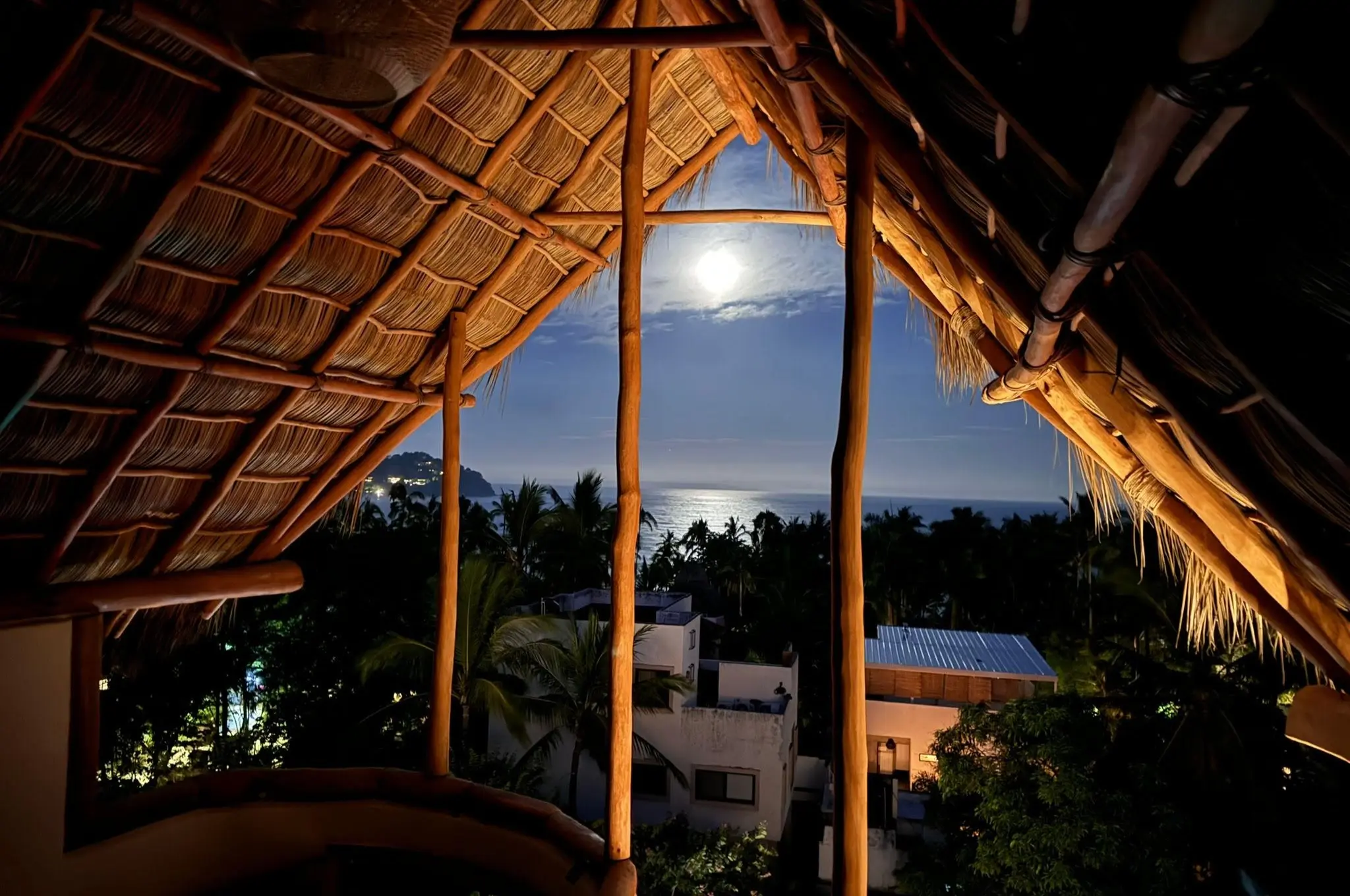 Moonlight glows over the ocean beyond a warm palapa hideaway at Amari Boutique Hotel Sayulita, made for tranquil nights.
