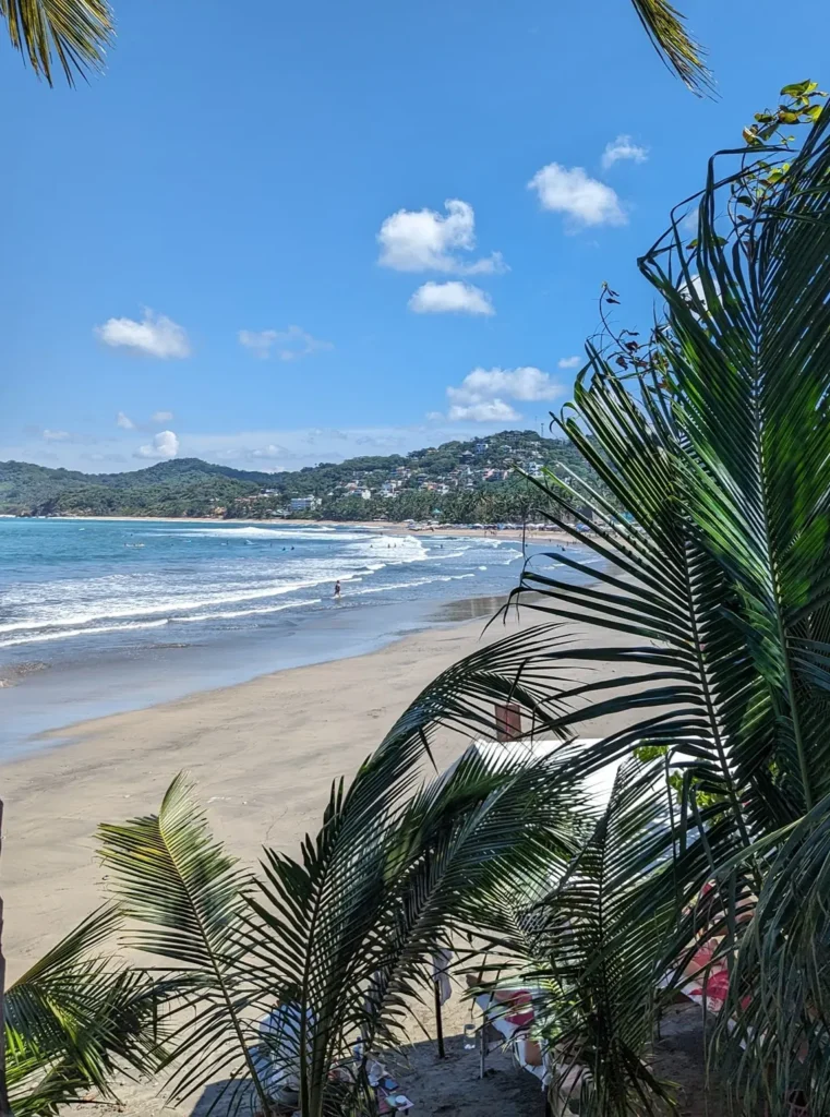 A sunny morning view over Sayulita’s shoreline shows waves, palms, and hills creating a calm coastal backdrop for a relaxing start to the morning