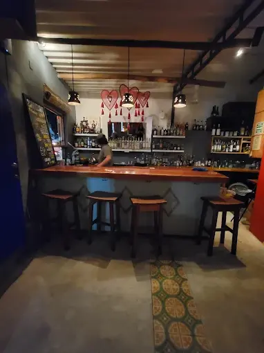 Small bar in Sayulita with soft evening lighting, shelves of tequila and mezcal, and a bartender preparing drinks.