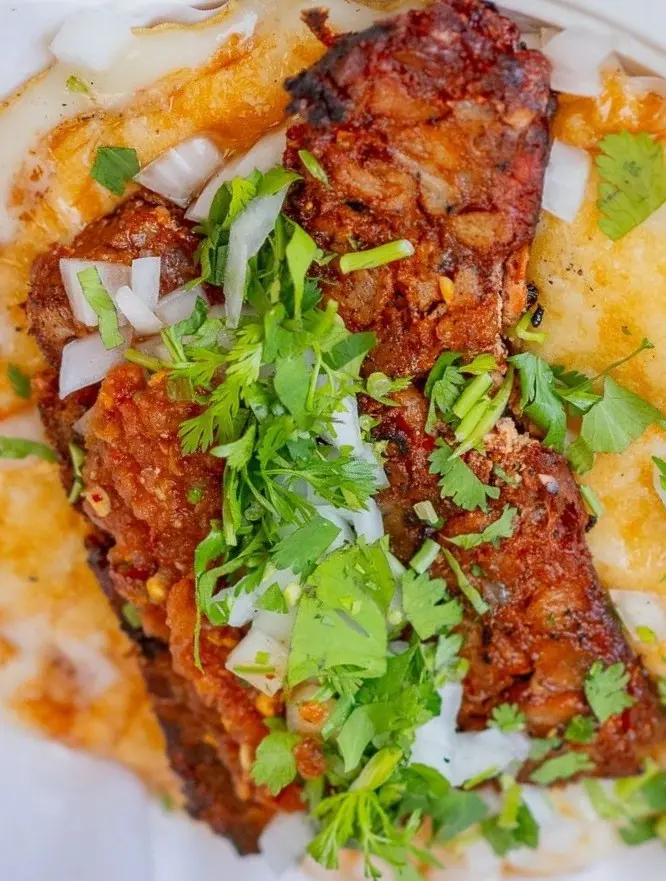 Chorizo taco on a tortilla topped with onions and cilantro, showing spicy red sausage and glossy juices for a bold Mexican street-food favorite bite.