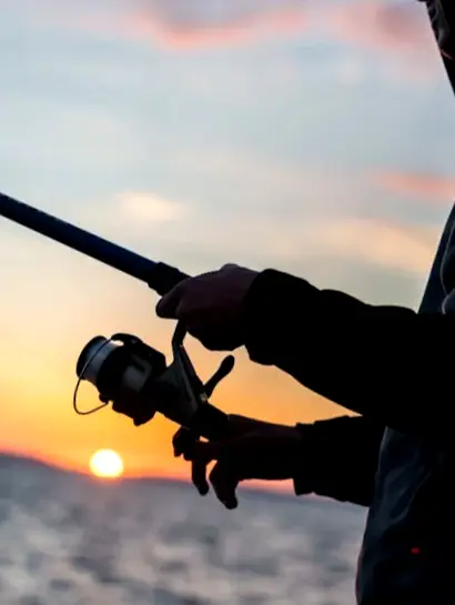 An angler prepares to cast at sunrise on Sayulita’s shore, holding a spinning rod during a calm early morning of shoreline fishing.