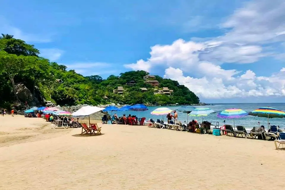 Bright umbrellas and beach chairs line Sayulita’s main shore, where families and travelers enjoy sunlit moments along the vibrant Nayarit Beachfront.