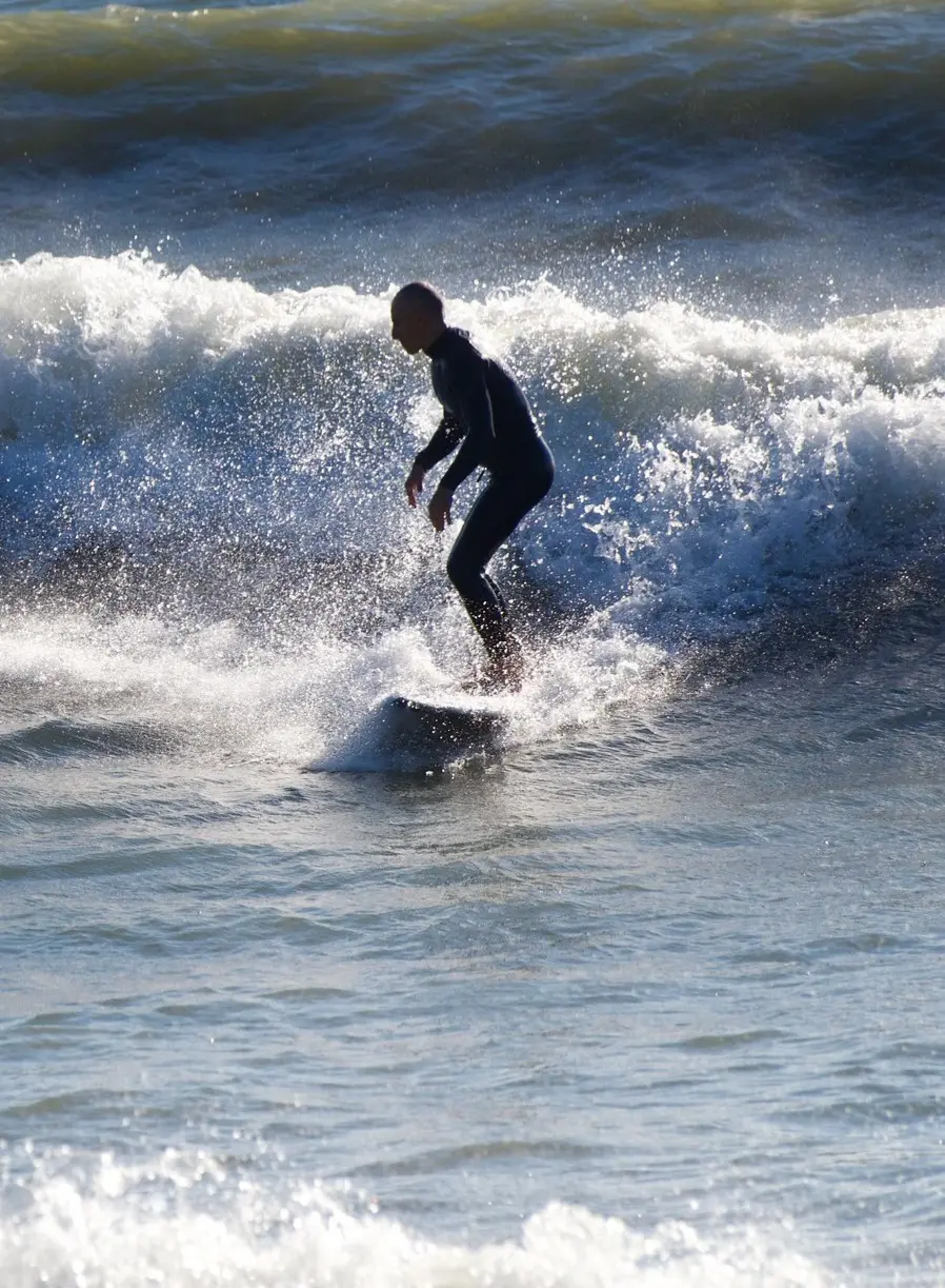 A surfer glides through soft golden waves as music drifts from shore—capturing Sayulita’s laid-back surf energy along the serene Pacific Riviera of Mexico.